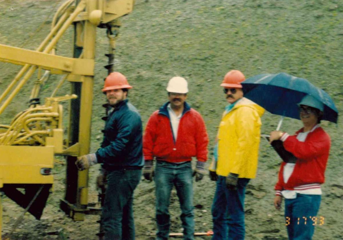 Tony Boland and fellow Tulare County Public Works employees stand beside a drilling rig at a field work site during a project in November 1993.