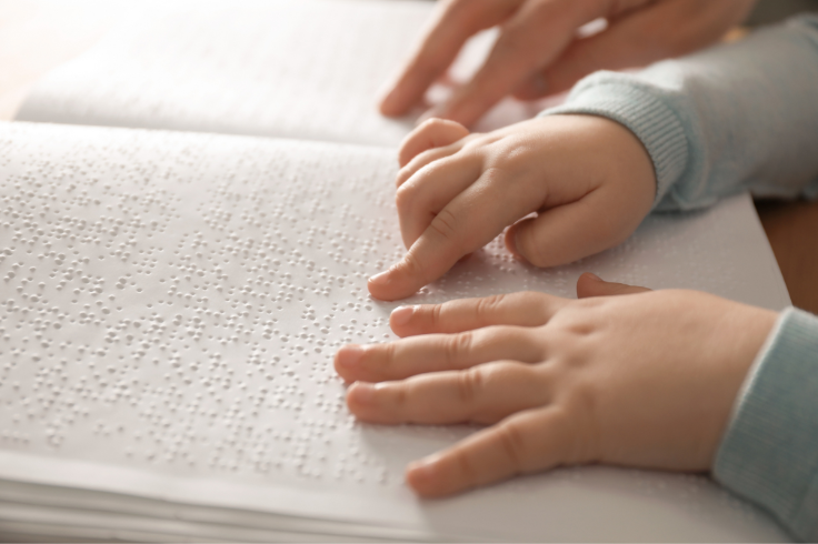 Children's hands reading braille