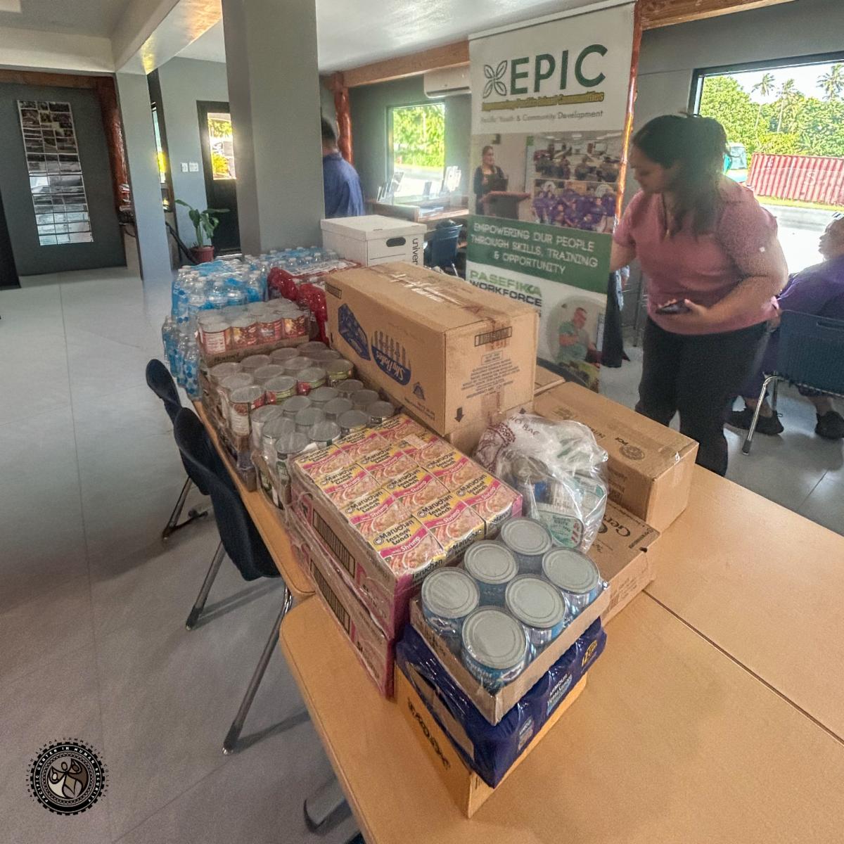 Donations, canned food, water, instant noodles on a table.