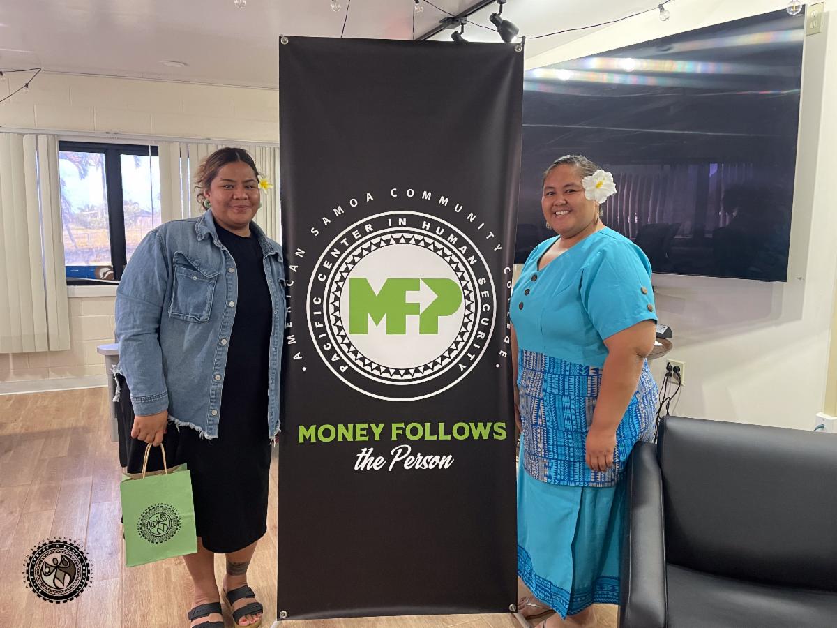 Charisma and Tumanu posing next to the Money Follows the Person banner.