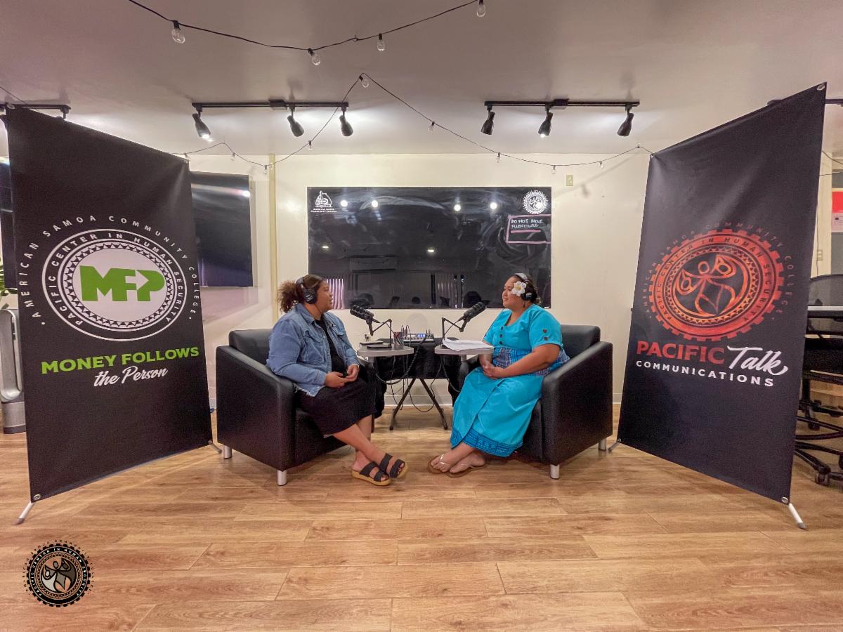 Charisma and Tumanu with podcast mics and headphones in a classroom with Money Follows the Person and Pacific Talk: Communications banners in the back