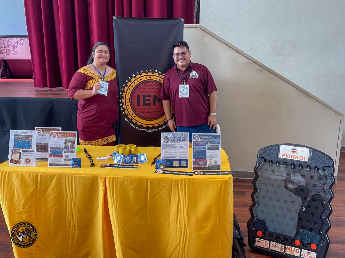 iEM trainees at a booth with flyers and signs about the degree program.