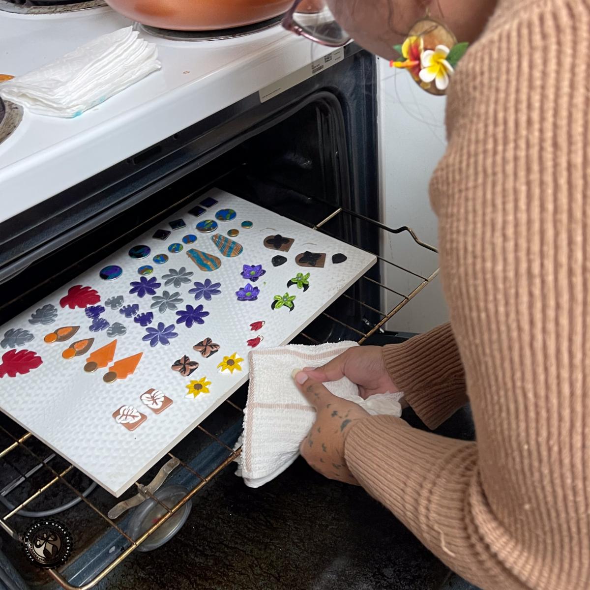 Artist taking out clay earrings from oven. 