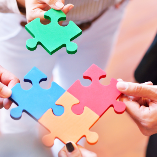 Different hands putting together puzzle pieces. 