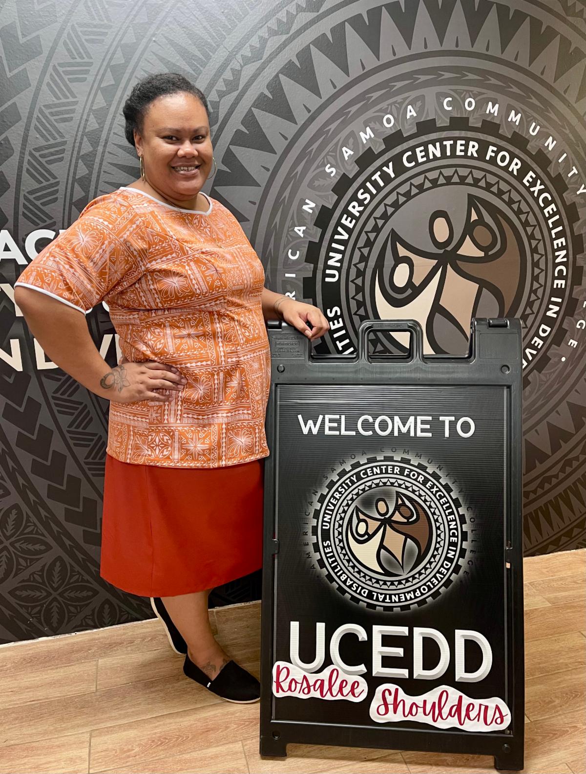 Newly hired Project Manager, Rosalee Shoulders, with welcome to UCEDD sign. 