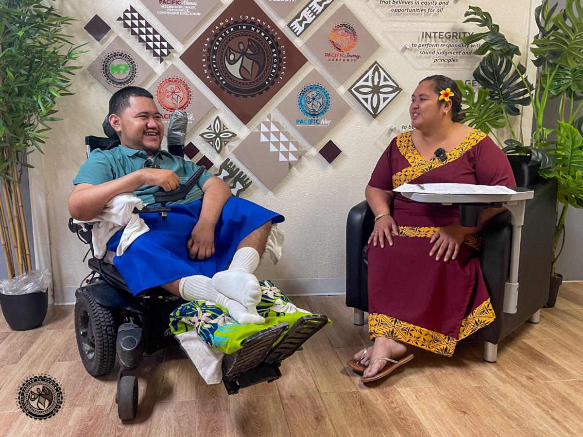 Alofa and Tumanu in discussion with smiles, in front of video cameras