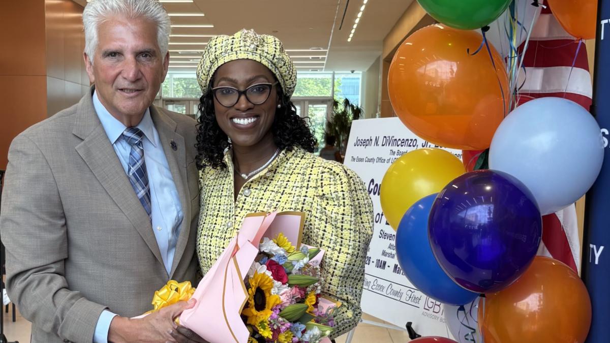 man and woman in room with balloons and woman is holding a bouquet and smiling