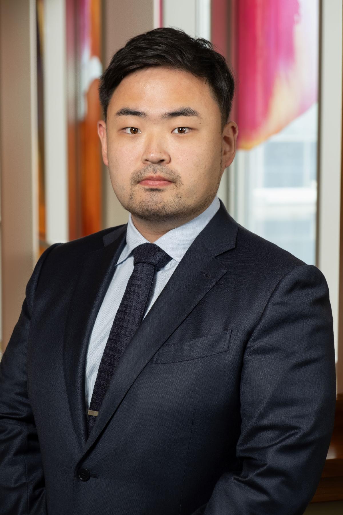 man in business suit, slightly turned, in front of large colorful window