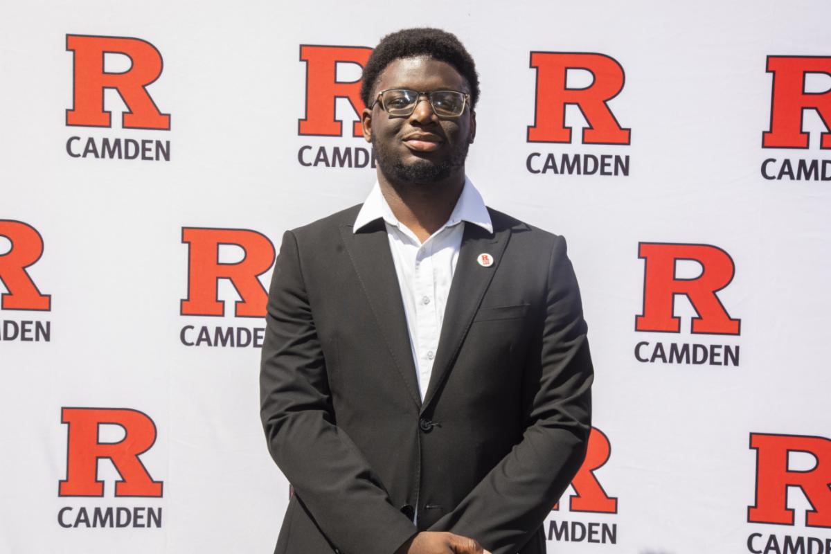 man wearing glasses with hands folded in front of him standing in front of R Camden step and repeat