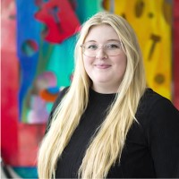 woman wearing glasses smiling in front of colorful artwork