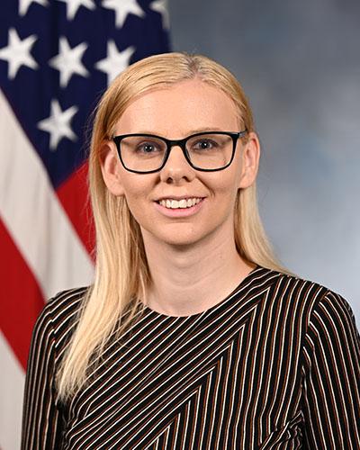 woman wearing glasses smiling in front of American flag