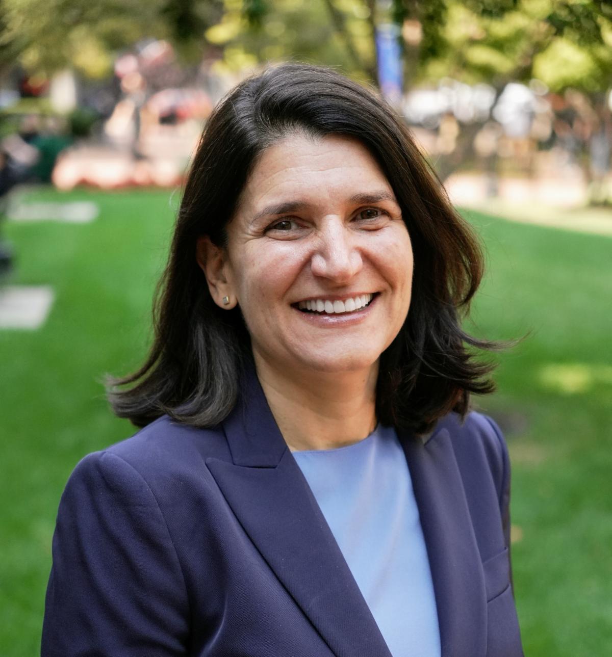 woman in blue blazer and blouse outdoors smiling