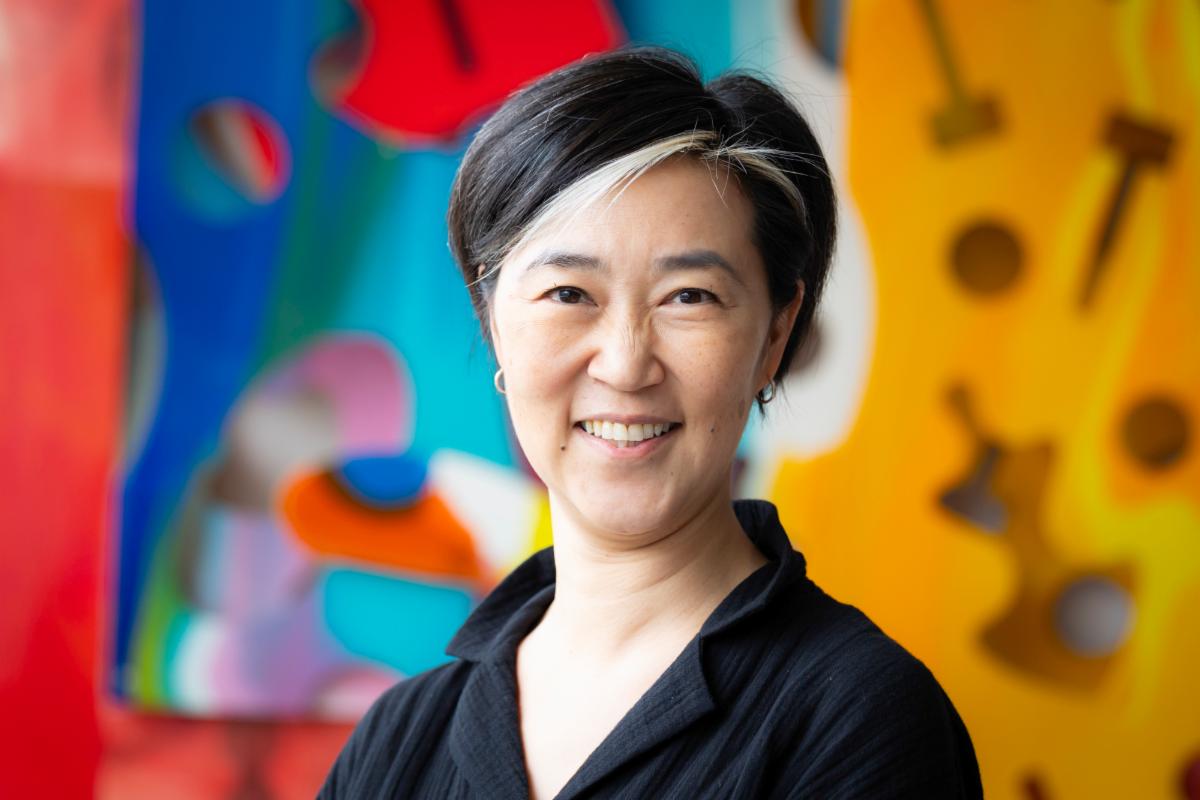 woman smiling in front of colorful artwork