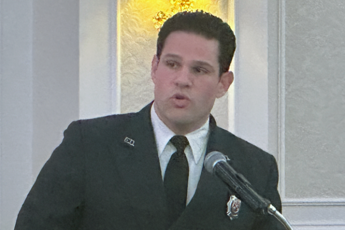 man in dark suit speaking in mic