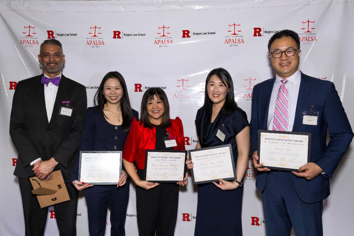 group of people in business attire holding certificates against backdrop with logos