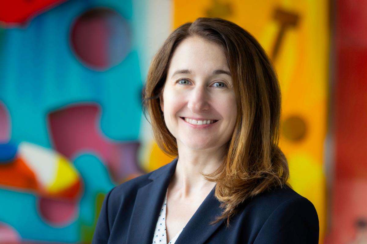 woman smiling in front of colorful artwork