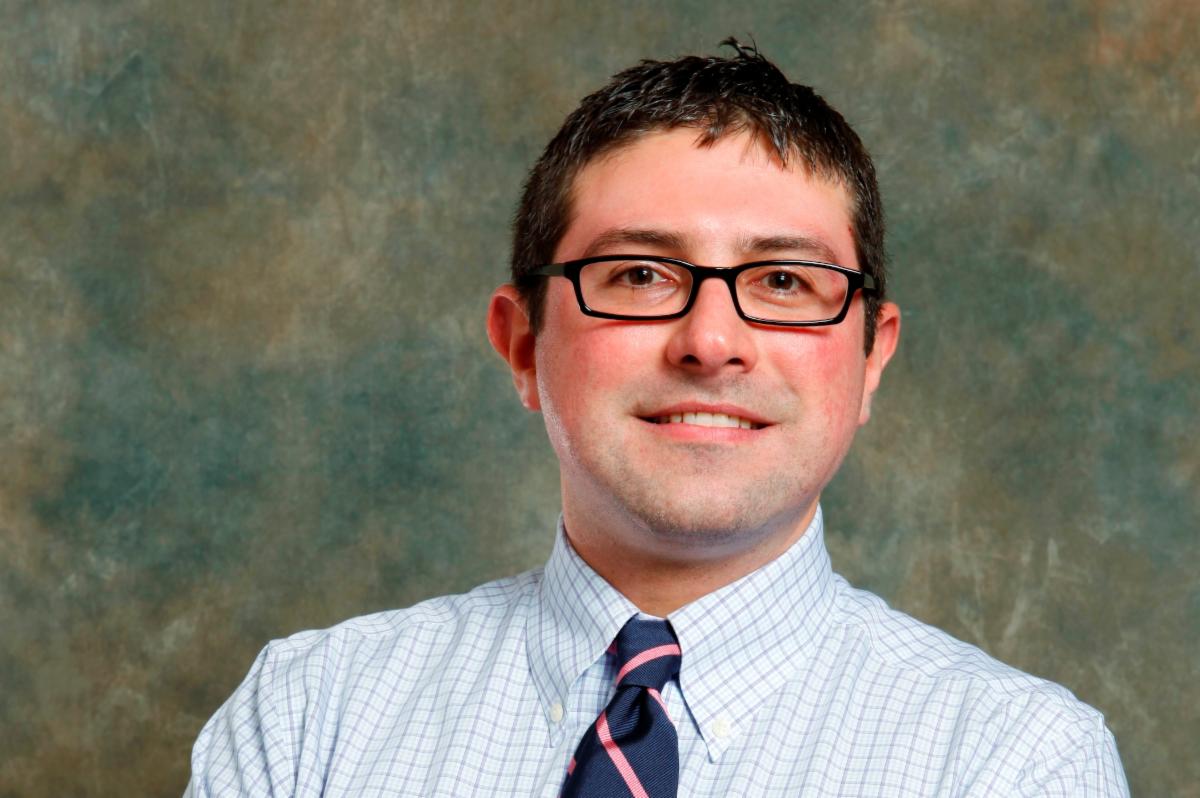 man smiling and wearing glasses in shirt and tie