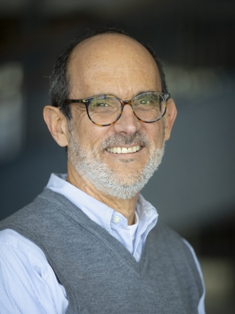 man in blue shirt and gray vest smiling 