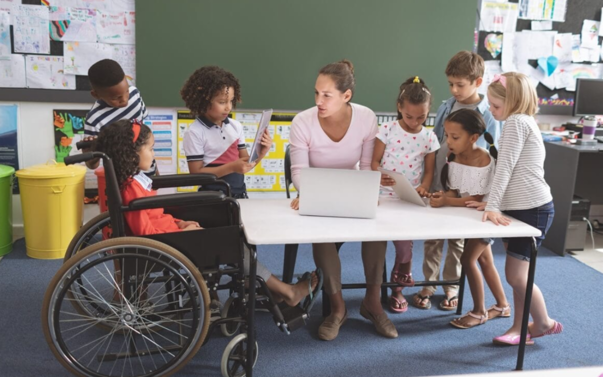 Teacher surrounded by students, showing inclusion of a student in a wheel chair