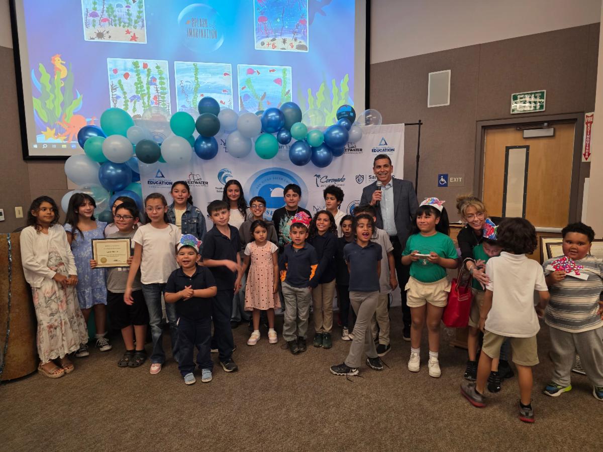 Group of students standing at front of stage with balloons and under the sea themed decorations