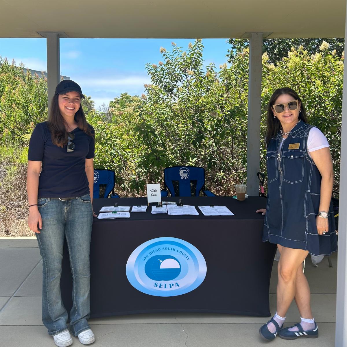SELPA team members standing at each end of an informational table outside