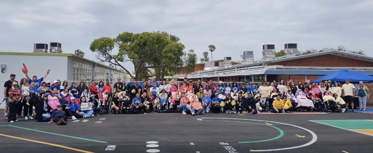 Students staff and volunteers posing together for a group photo on Friendship School's blacktop