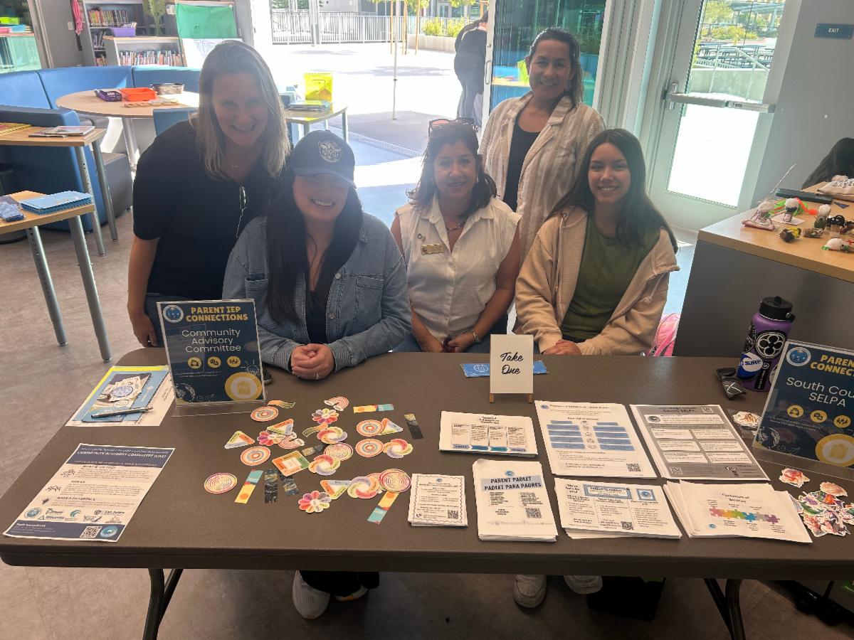 SELPA team members and CAC members sitting together at a table with flyers and stickers