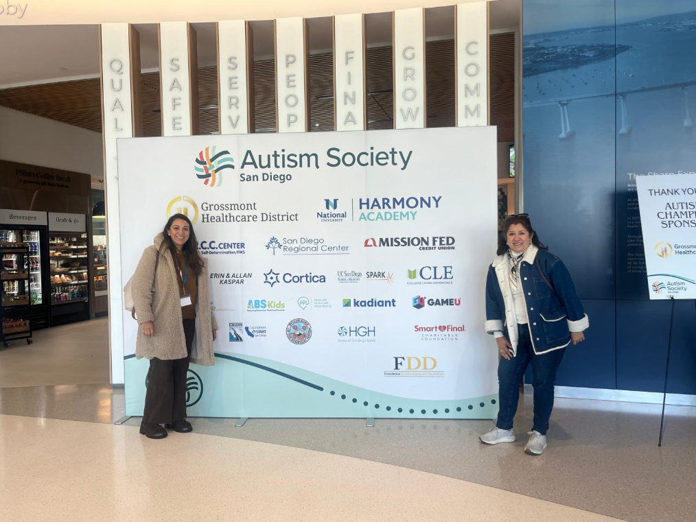 Staff member and parent posing at the entrance of the Autism Society Conference