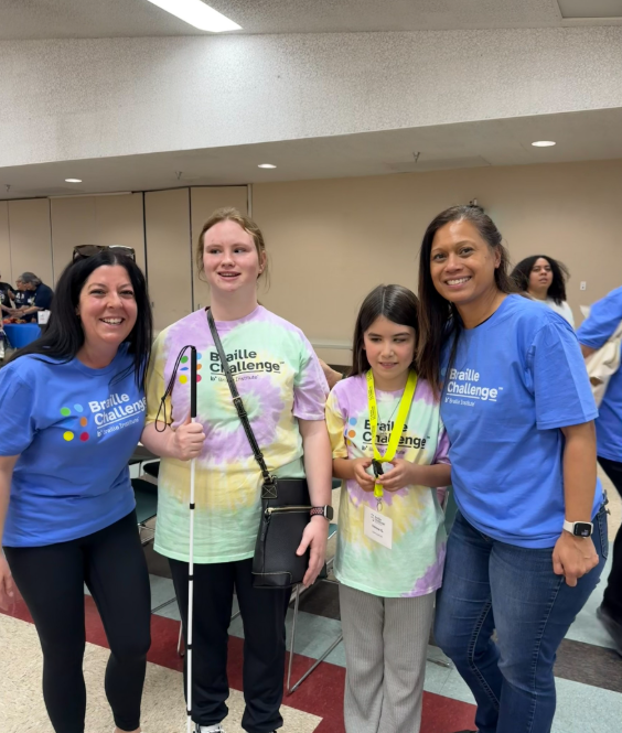 Teachers of students with visual impairments posing with two students participating in the Braille Challenge