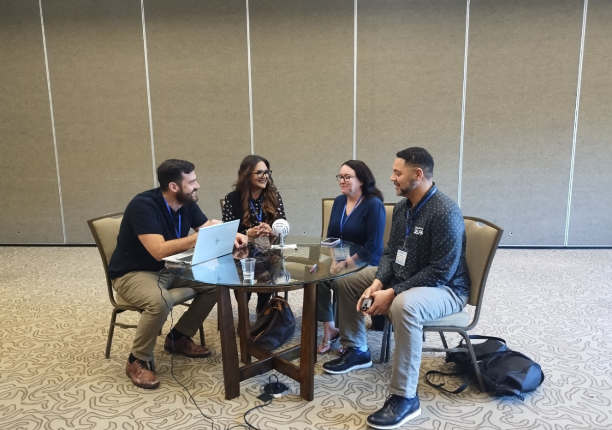 Four members of a podcast episode sitting around a table conversing