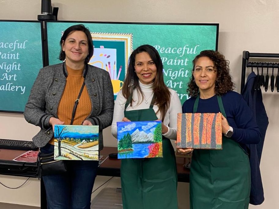 Photo of three participants from Paint Night holding their completed paintings