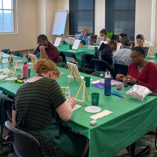 Photo of participants working on their paintings at a paint night event.