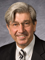 A headshot photo of a man wearing a suit and tie