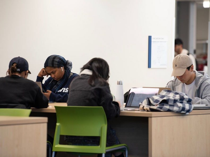 group of students studying at a table with laptops