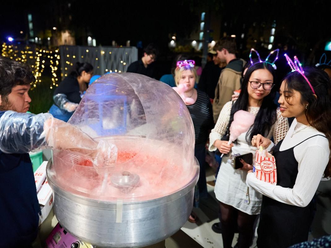 People in formal wear standing around a cotton candy machine