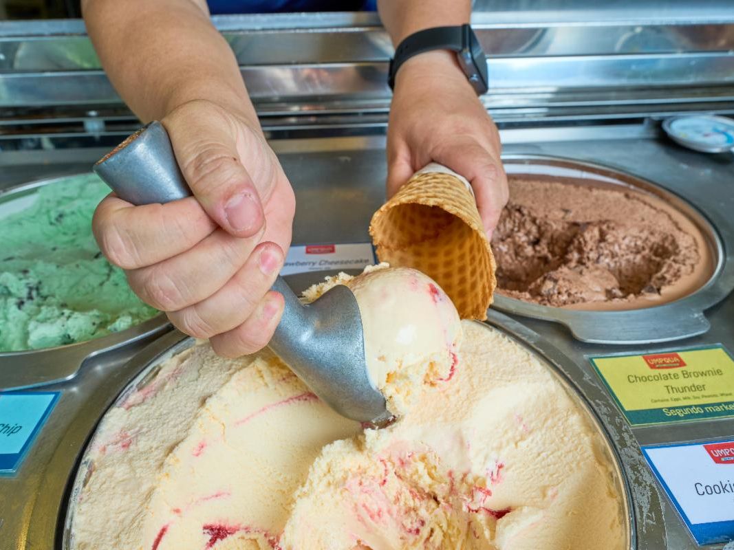 Someone scooping ice cream into a cone