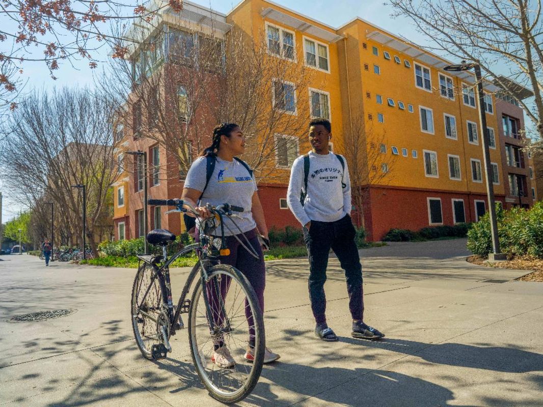 Two students and one with a bike outside tercero residence halls
