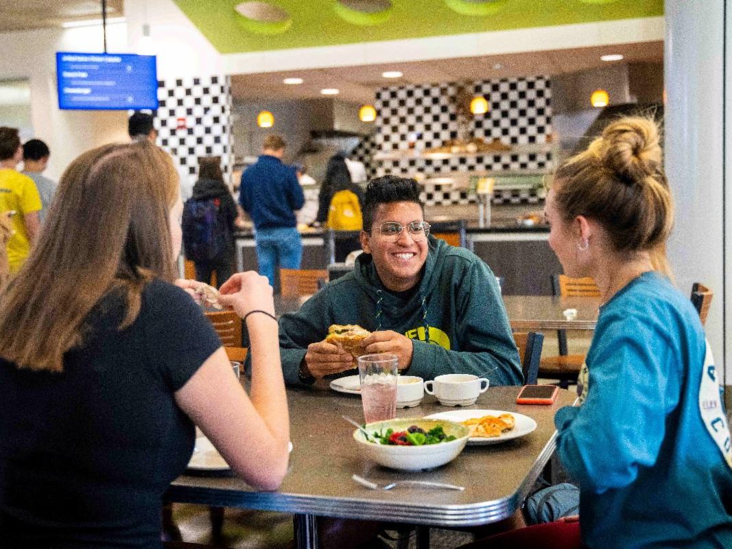 A man and two women eating at the UC Davis dining commons.