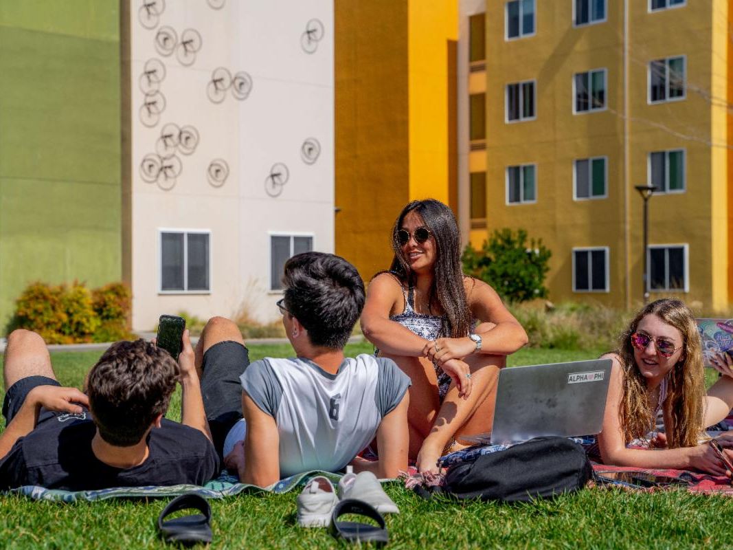 Students lounging on lawn in front of residence halls.