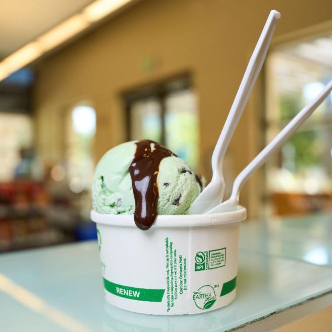 Someone scooping ice cream into a cone