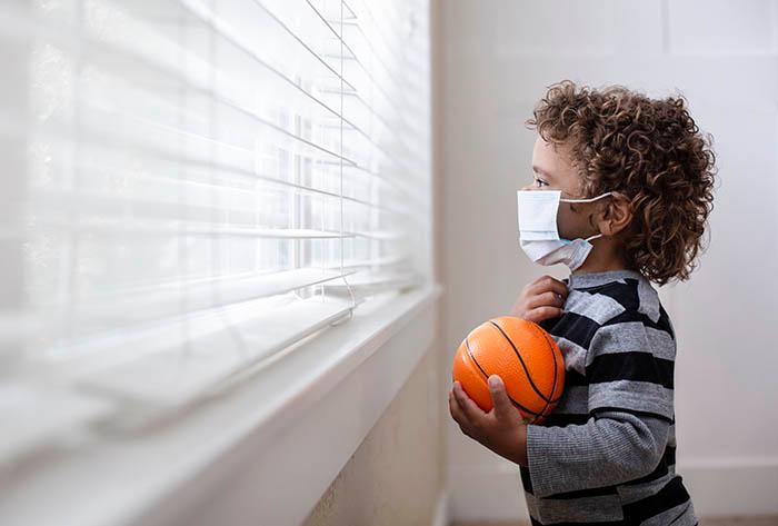 little boy with mask looking out window