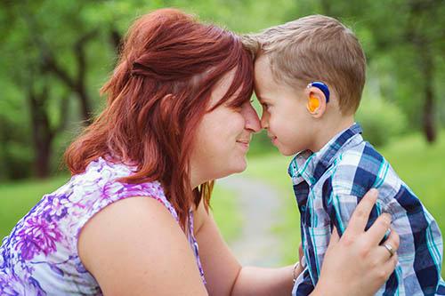 woman hugging boy with hearing aids