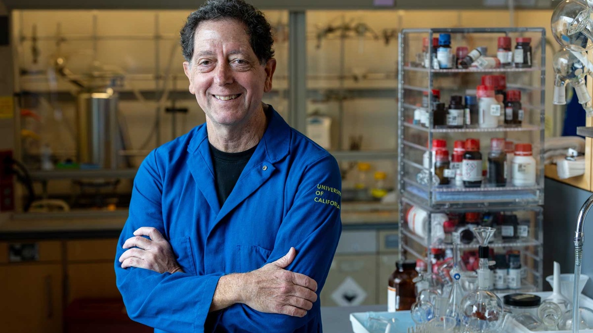 Kevan Shokat wears a blue lab coat as he stands in his lab at U C S F.