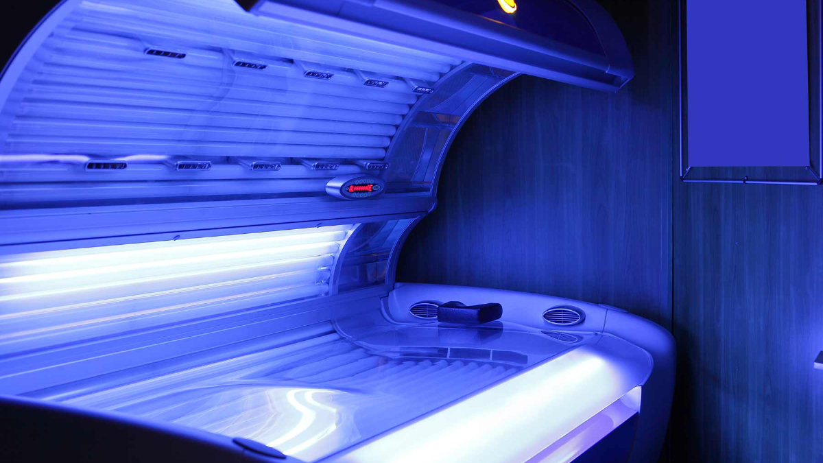 An open tanning bed glows in a dark room