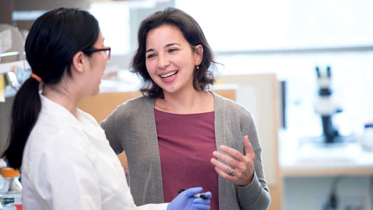 Two women causally speak in laboratory.