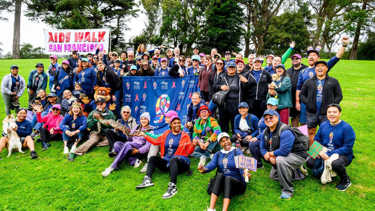 Large group of AIDS Walk San Francisco participants gather on a lawn with a UCSF banner, smiling for a team photo.