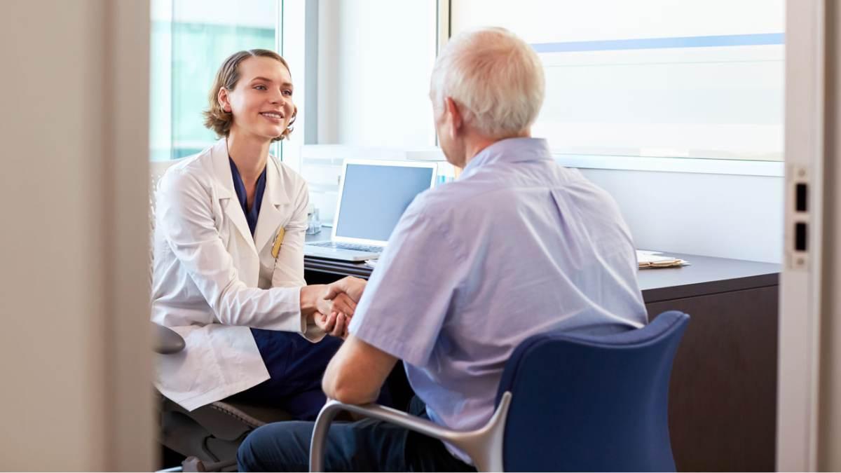 Doctor shaking hands with an older patient in an exam room