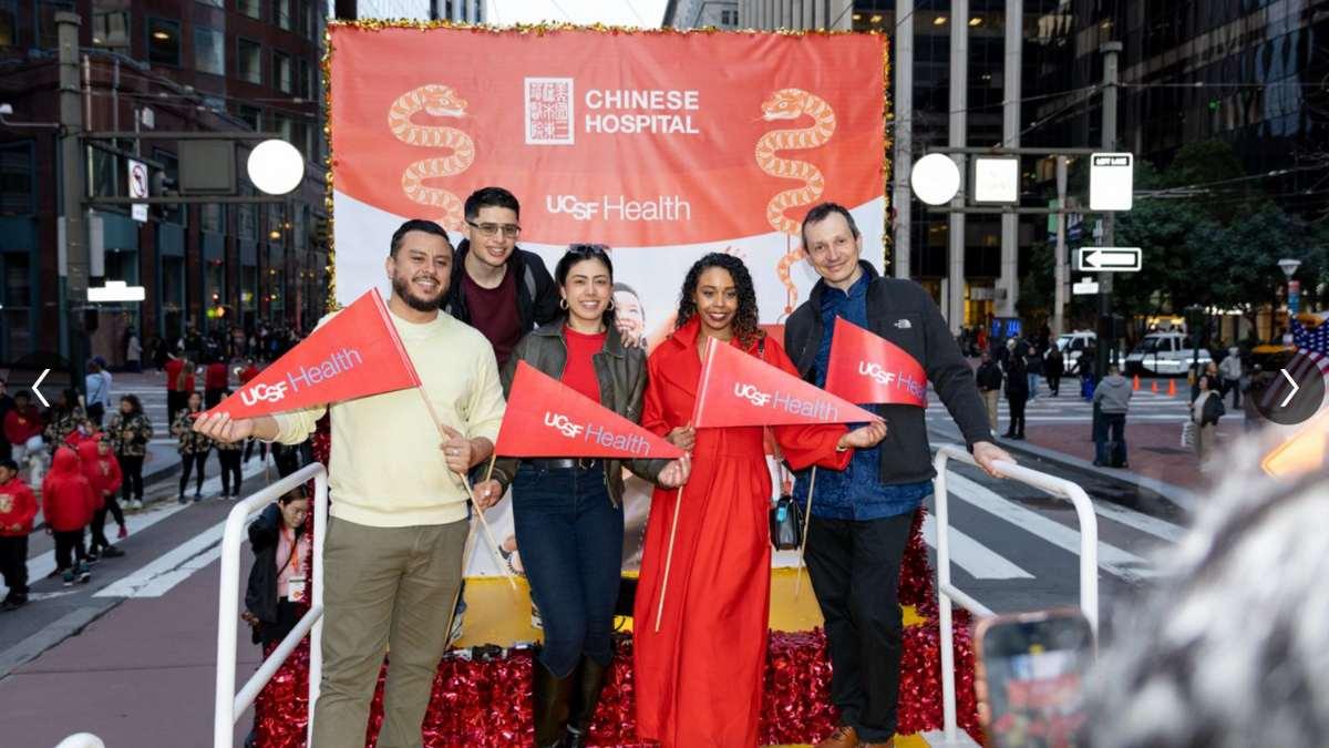 Group of people wave flags on a step and repeat.