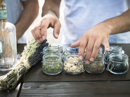 A person putting dried herbs in small glass jars