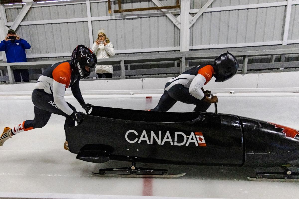 Bobsleigh brakeman Luke Puto pushes his sled
